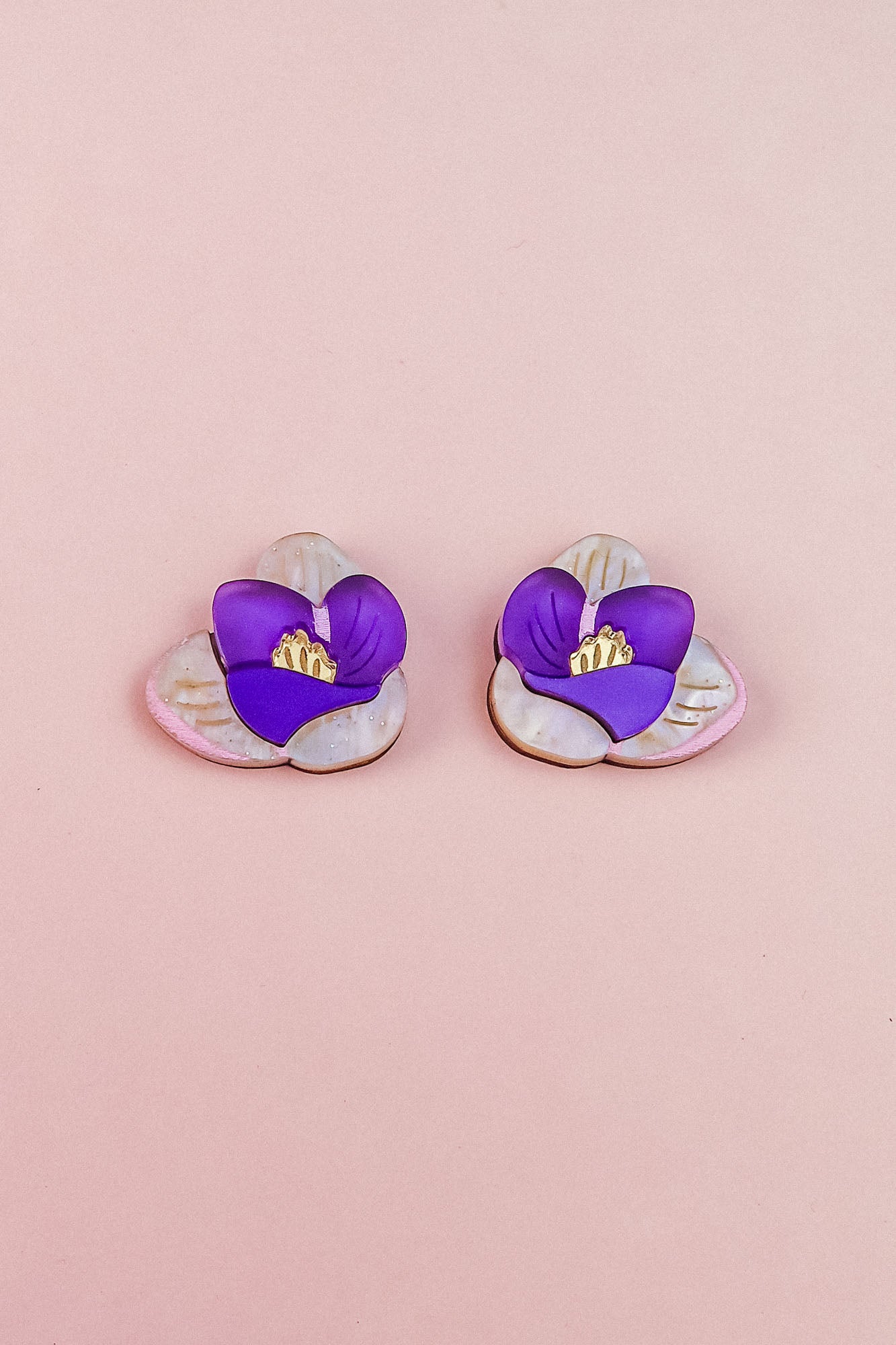 Crocus Stud Earrings featuring hand-painted flowers in purple and white with yellow centers, beautifully displayed on a light pink background.